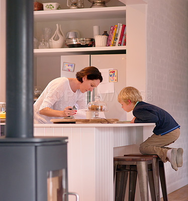 Buy stock photo Shot of a cute little boy watching his mother work in their kitchen at home