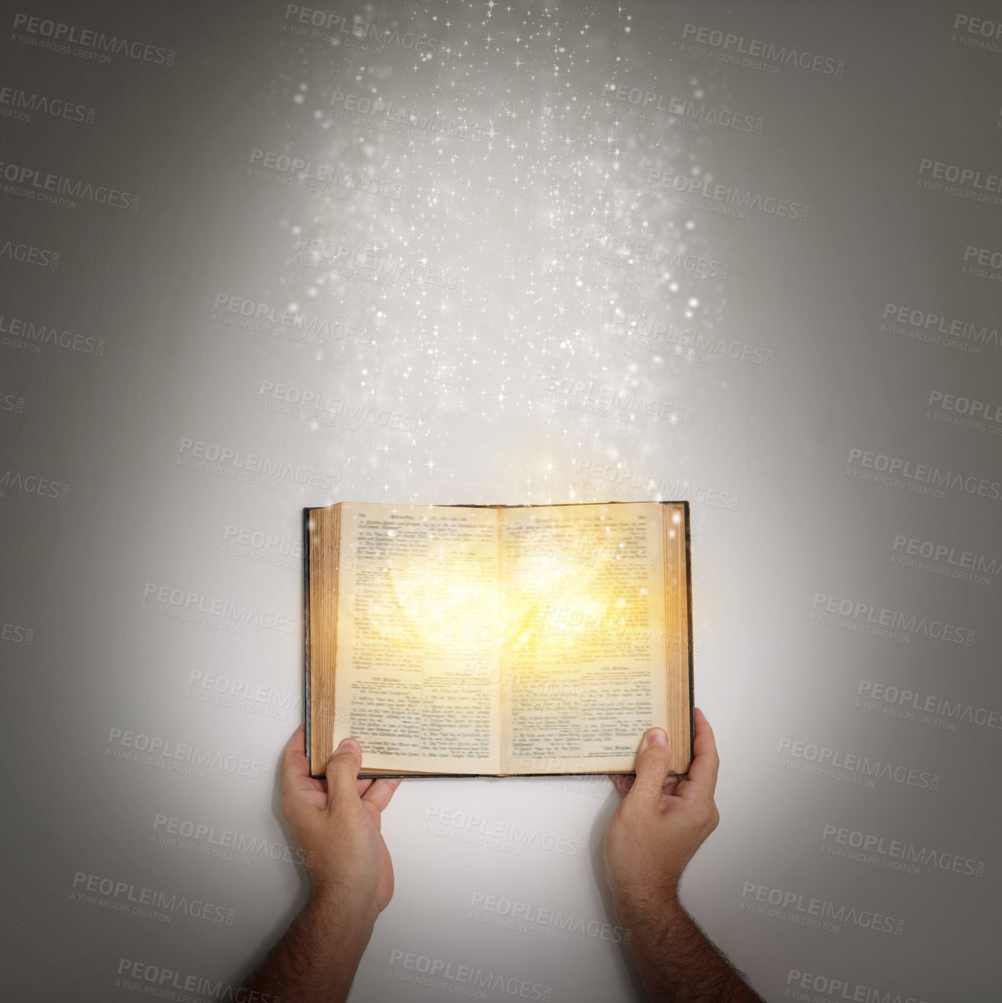 Buy stock photo Shot of a hand holding an open storybook with light emanating from it