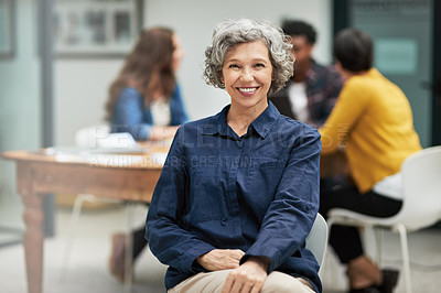 Buy stock photo Portrait of a creative businesswoman sitting in the office while her colleagues work in the background