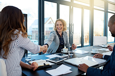 Buy stock photo Shot of two corporate businesswomen shaking hands during a meeting in the boardroom