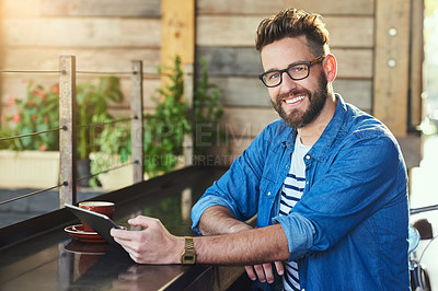 Buy stock photo Portrait of a handsome young man working on a digital tablet in a cafe