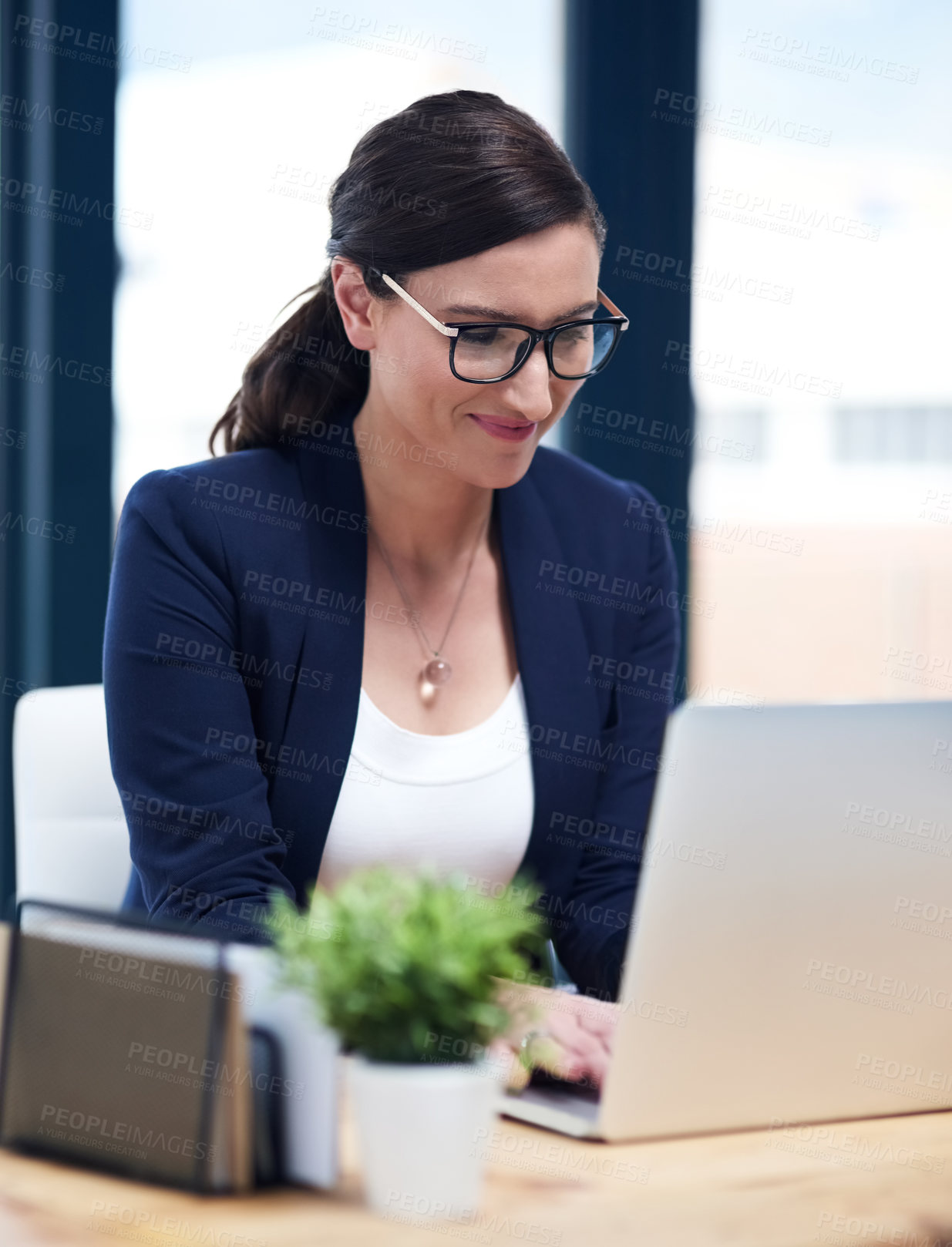 Buy stock photo Shot of a busy businesswoman working on her laptop in her office