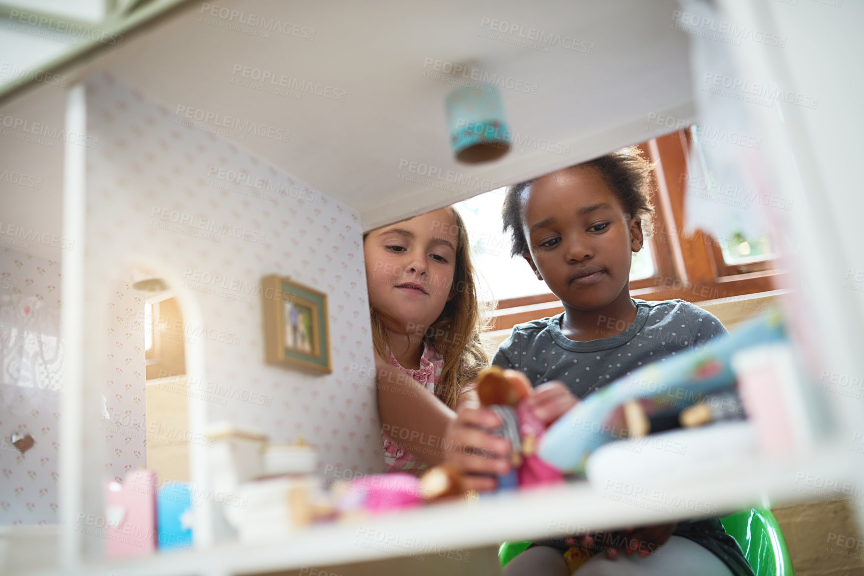 Buy stock photo Cropped shot of two friends playing together with a dollhouse