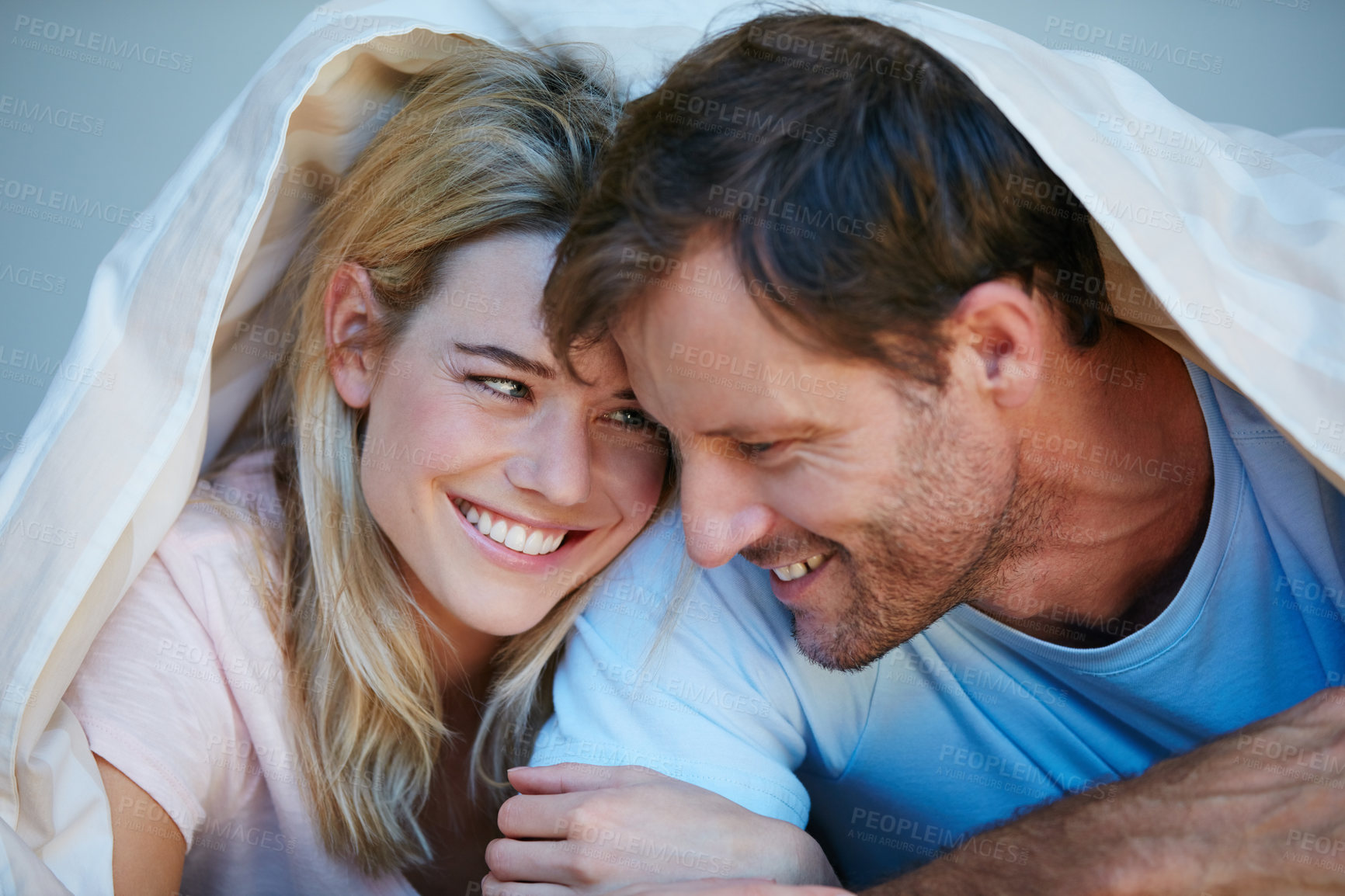 Buy stock photo Shot of a happy couple lying together in bed