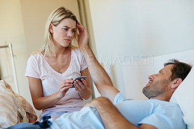 Buy stock photo Shot of a woman looking upset as she goes through her husband's phone
