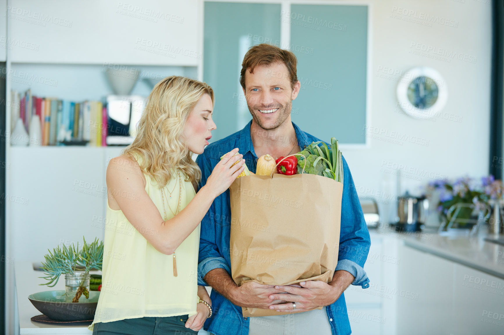 Buy stock photo Shot of a happy couple holding a bag full of healthy groceries at home