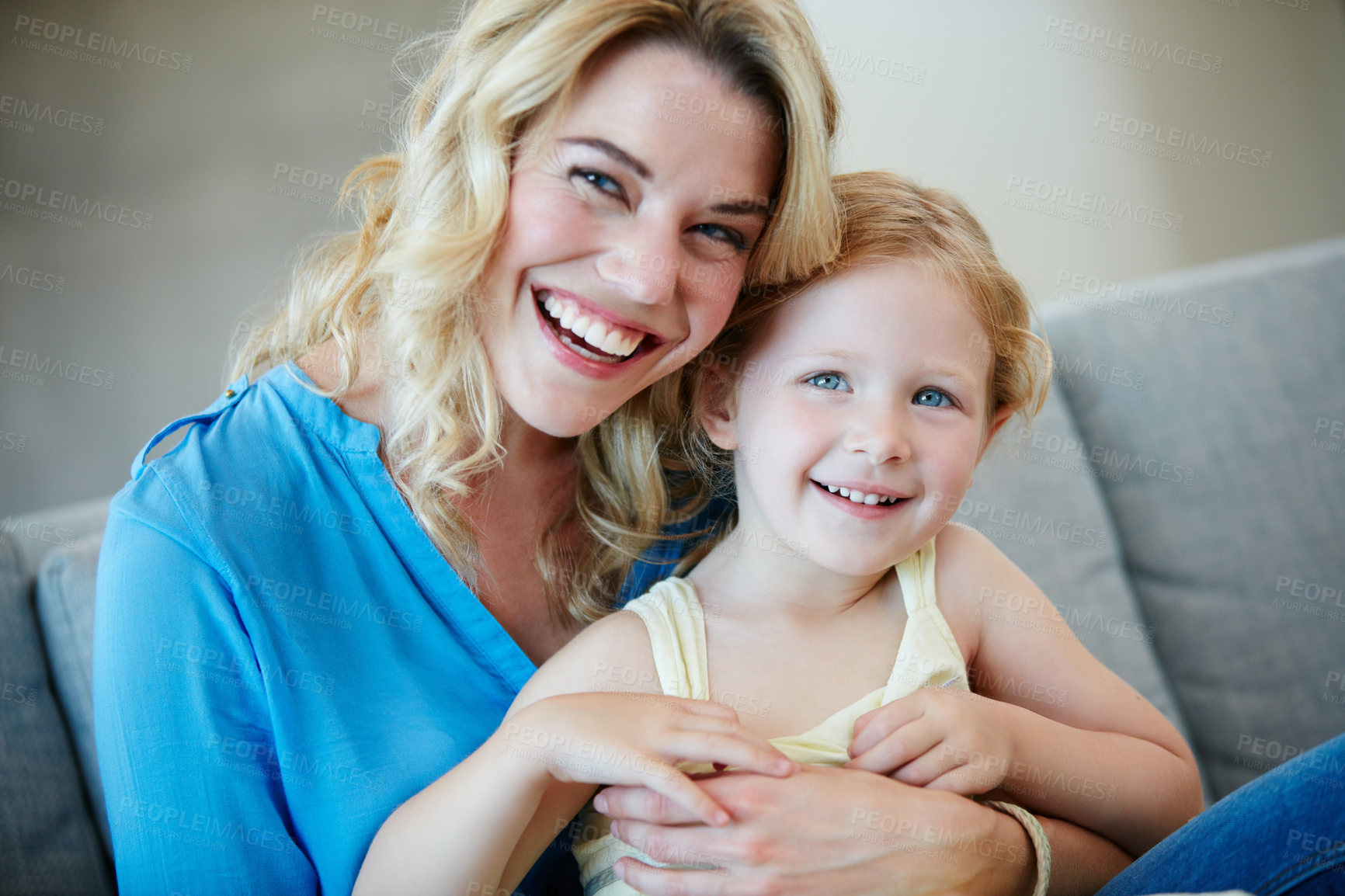 Buy stock photo Shot of a young mother and her daughter laughing while sitting on the sofa at home