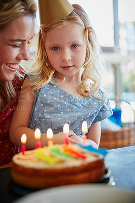 Buy stock photo Cropped shot of a little girl sitting with her mom in front of a birthday cake