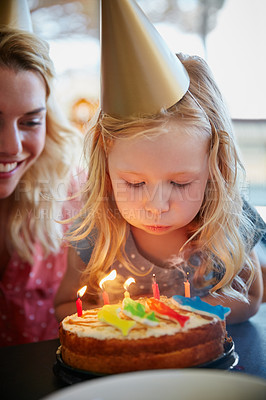 Buy stock photo Cropped shot of a little girl sitting with her mom in front of a birthday cake