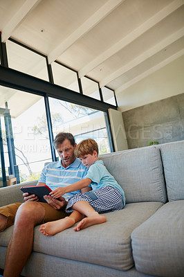 Buy stock photo Cropped shot of a father and son using a digital tablet together at home