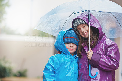 Buy stock photo Portrait of two siblings standing under an umbrella outside