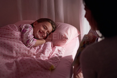 Buy stock photo Cropped shot of a little girl lying in bed while her mom reads a bedtime story