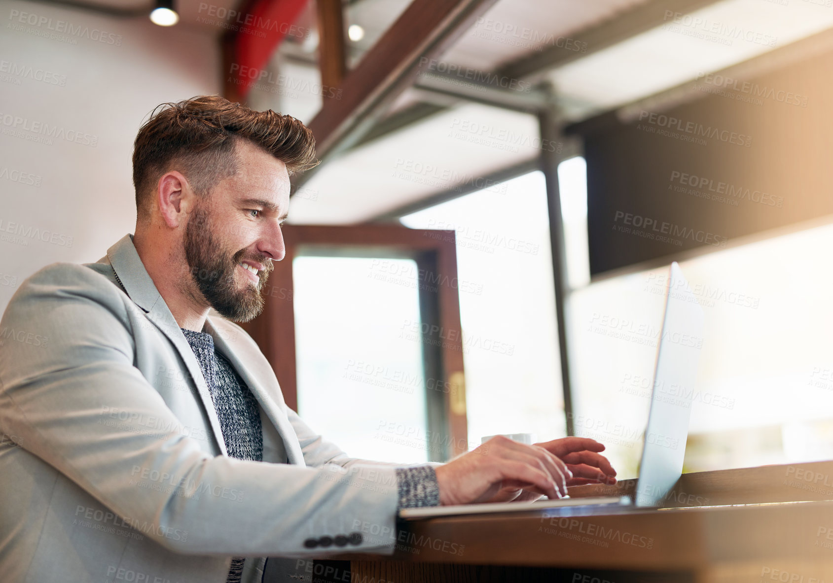 Buy stock photo Cropped shot of a modern businessman using his laptop in a coffee shop