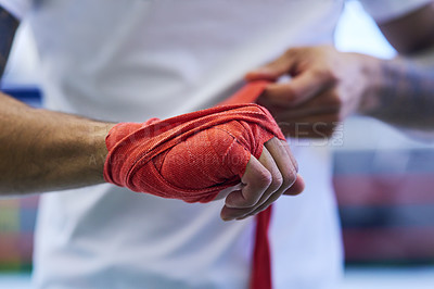 Buy stock photo Shot of an unrecognizable man strapping his hands and wrists in he boxing gym