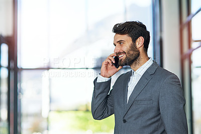 Buy stock photo Shot of a young businessman using a phone in a modern office