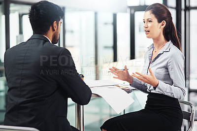 Buy stock photo Shot of two businesspeople talking together while sitting at a table in an office