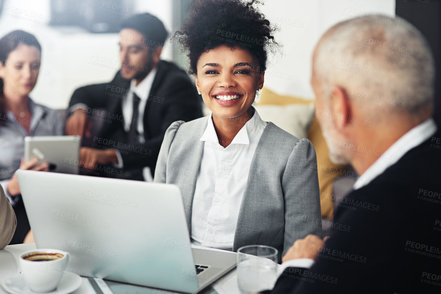 Buy stock photo Portrait of a smiling young businesswoman working on a laptop surrounded by colleagues