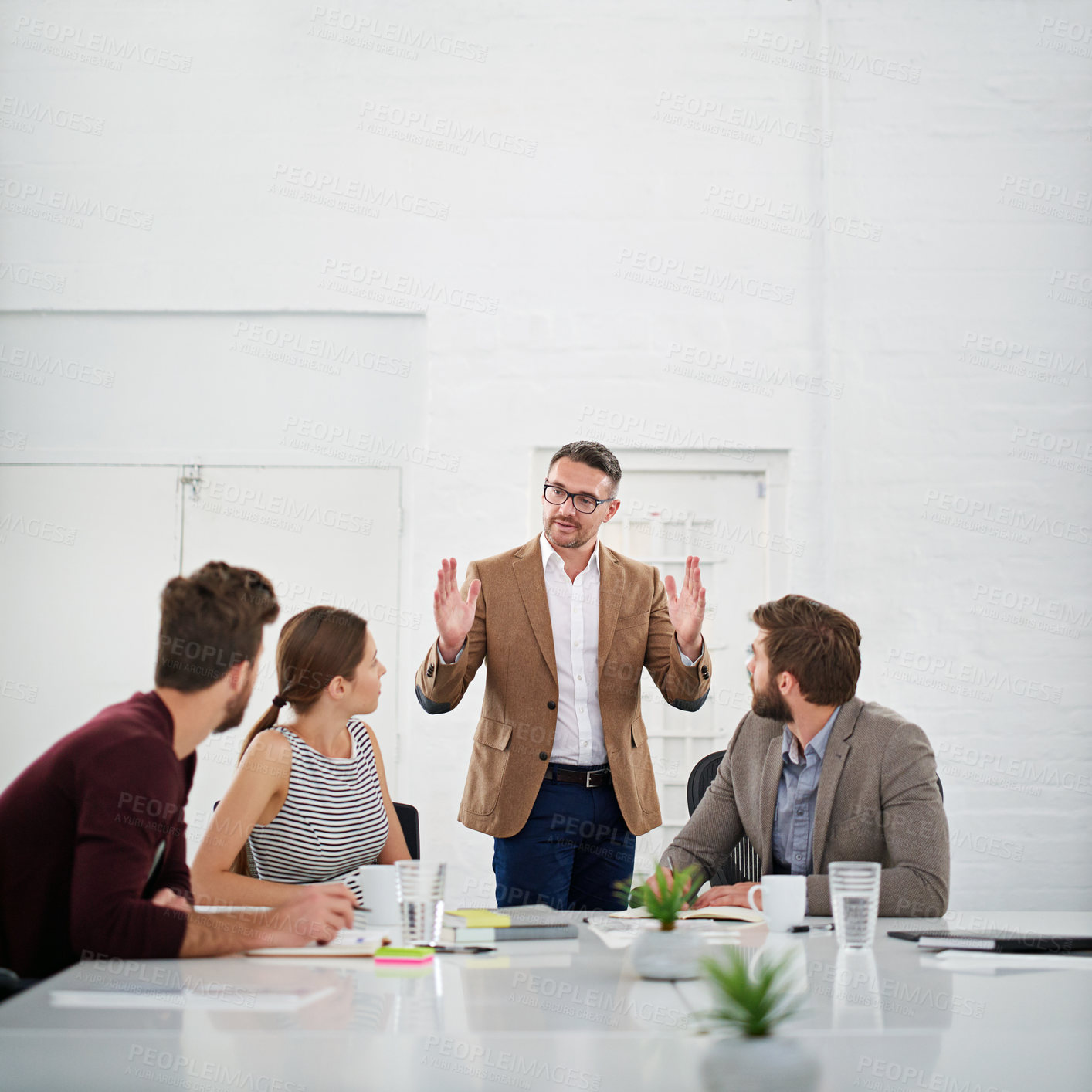 Buy stock photo Shot of a businessman giving a presentation to colleagues sitting at a table in a modern office