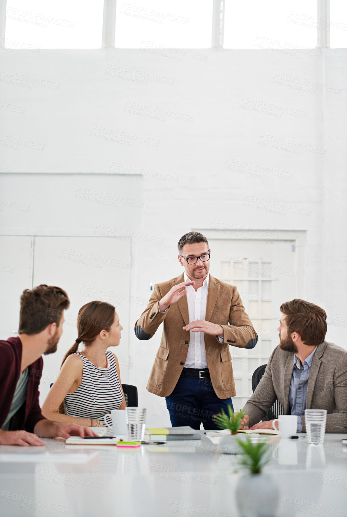 Buy stock photo Shot of a businessman giving a presentation to colleagues sitting at a table in a modern office