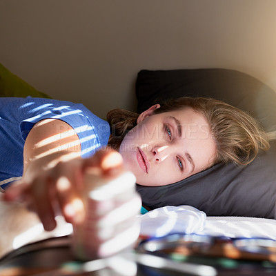 Buy stock photo Shot of a young woman waking up and reaching for her alarm clock at home