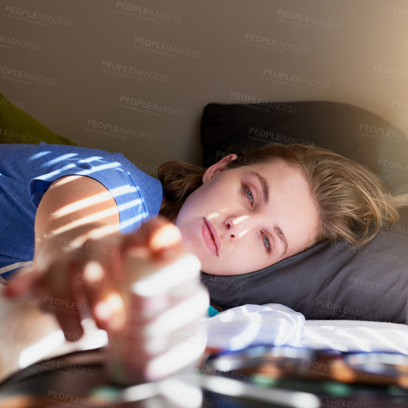 Buy stock photo Shot of a young woman waking up and reaching for her alarm clock at home