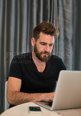 Buy stock photo Cropped shot of a young man using a laptop at home