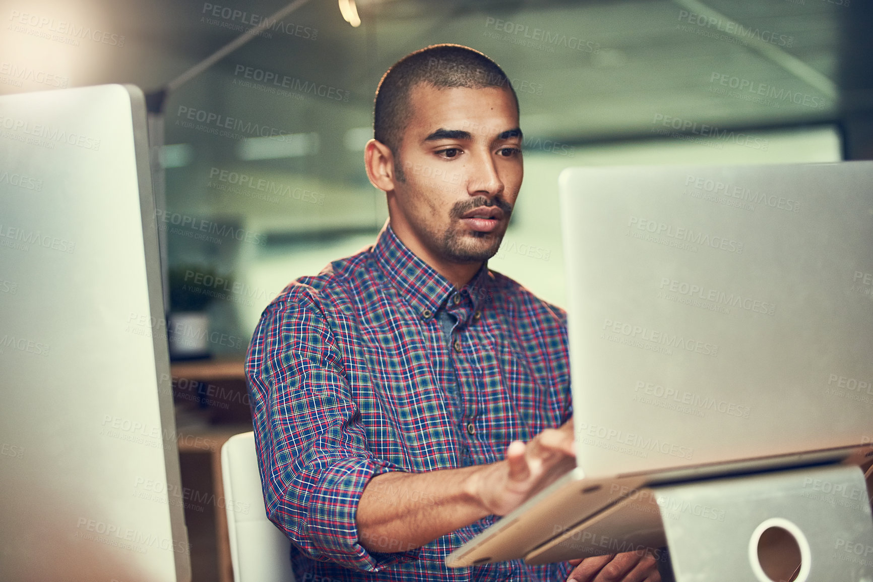 Buy stock photo Cropped shot of a young designer working late on a laptop in an office