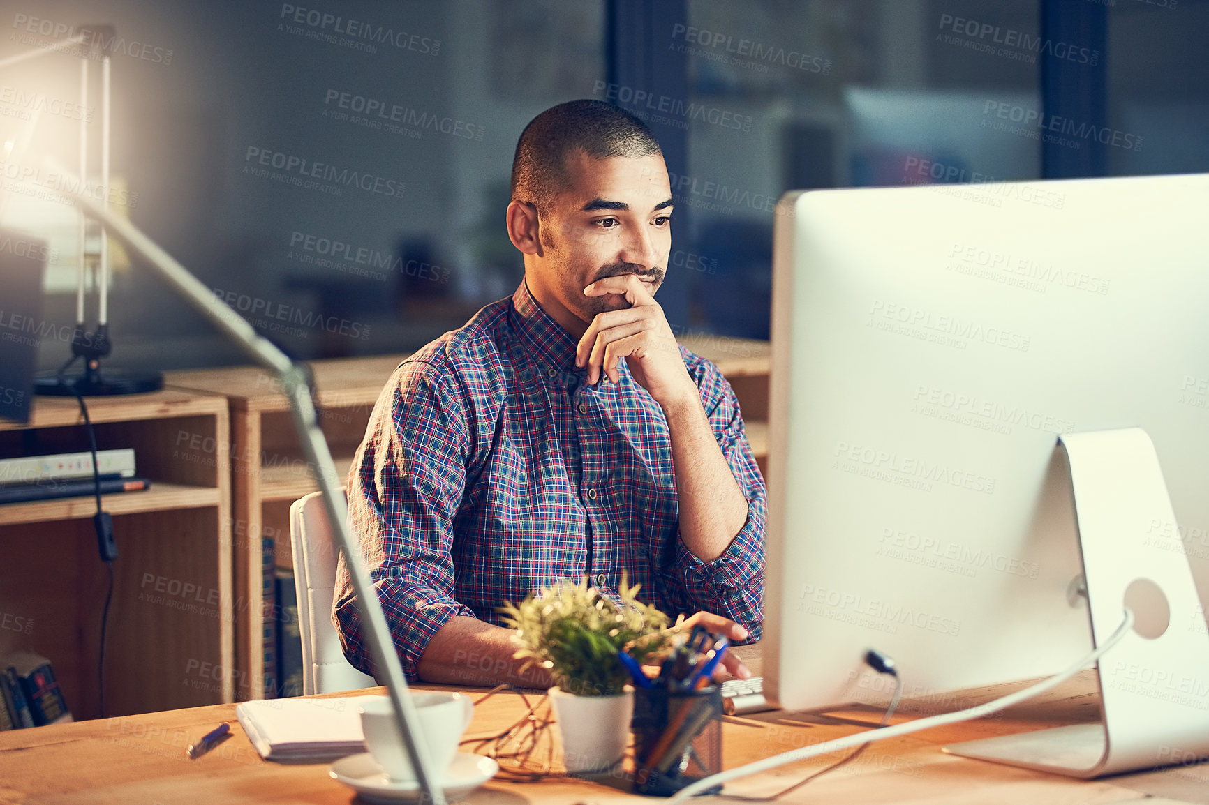 Buy stock photo Cropped shot of a young designer working late on a computer in an office