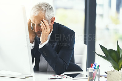 Buy stock photo Shot of a stressed out businessman working at his computer in an office