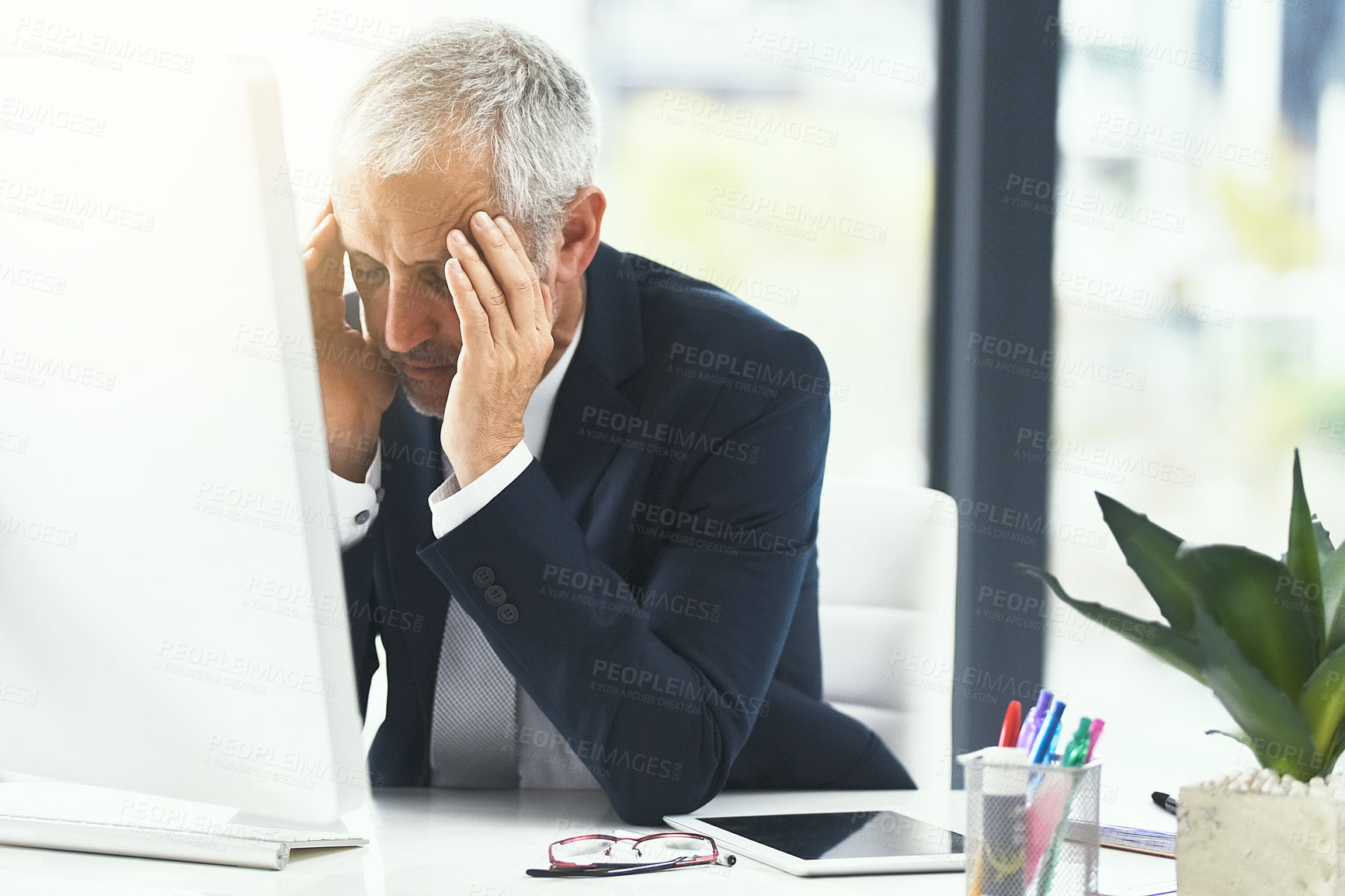 Buy stock photo Shot of a stressed out businessman working at his computer in an office