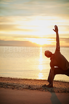 Buy stock photo Shot of a man practicing the triangle pose during his yoga routine at the beach