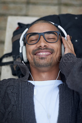 Buy stock photo Headphones, smile and man relaxing outdoor listening to music, radio or podcast at university. Happy, education and calm male student resting and streaming album, song or playlist at college campus.