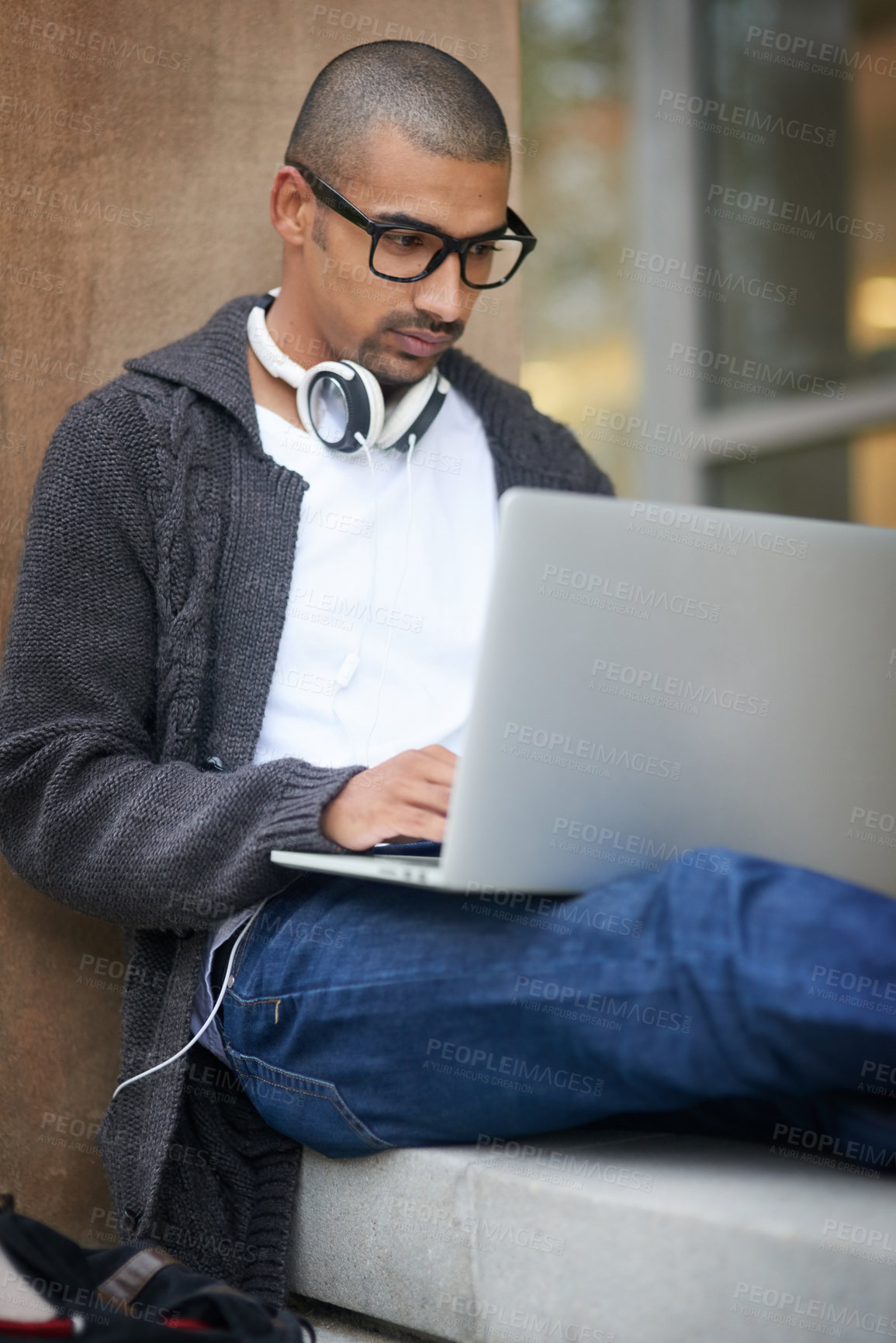 Buy stock photo Cropped shot of a college student using his laptop while sitting outside at campus