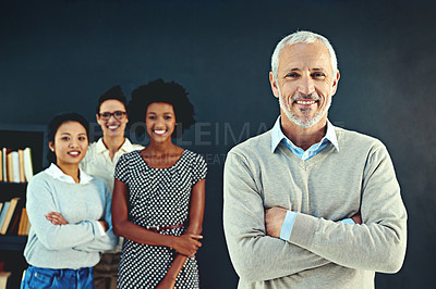 Buy stock photo Studio portrait of a mature businessman posing with his colleagues in the background