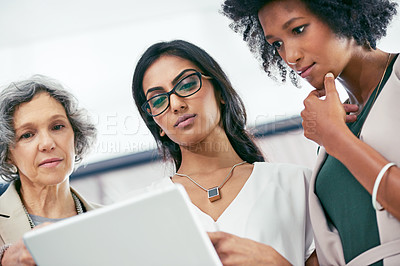 Buy stock photo Shot of a team of colleagues using a digital tablet during an informal meeting