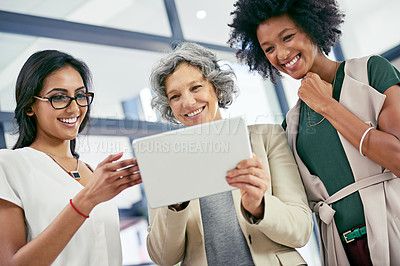 Buy stock photo Shot of a team of colleagues using a digital tablet during an informal meeting