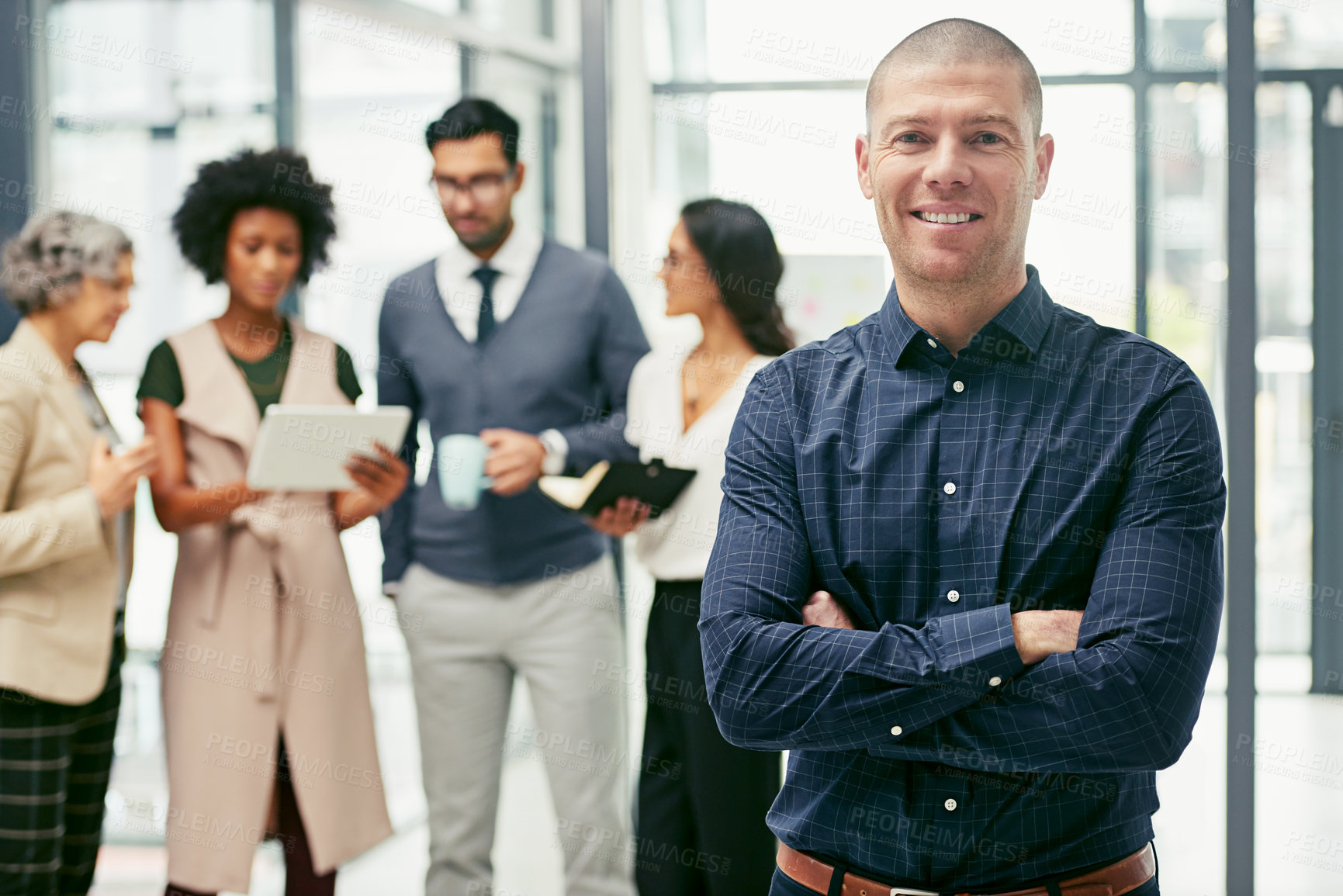 Buy stock photo Portrait of a businessman standing in an office with his colleagues in the background