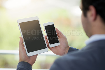 Buy stock photo Cropped shot of corporate businessmen looking at a digital tablet and a cellphone in his hands