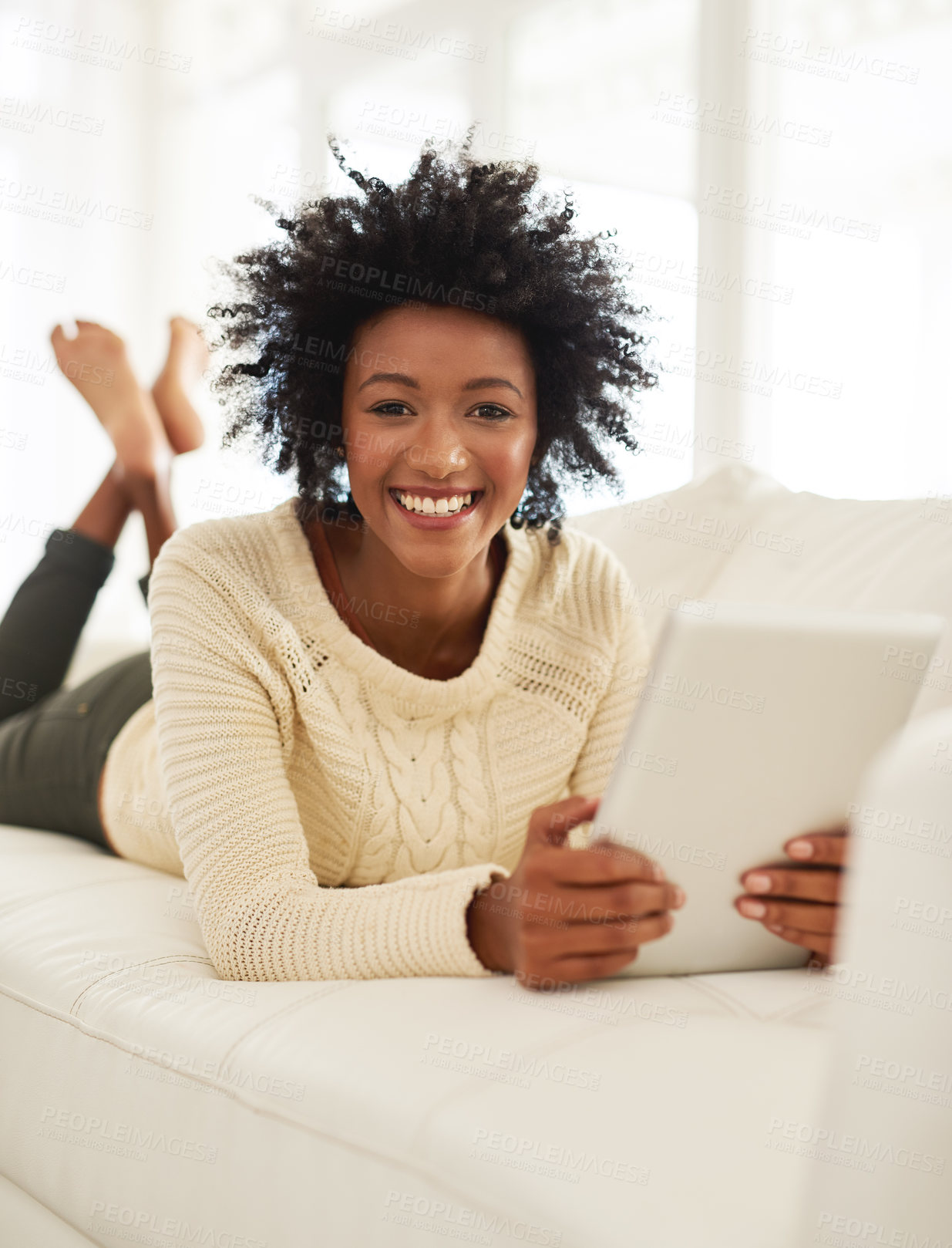 Buy stock photo Portrait of an attractive young using her tablet while lying on the sofa at home