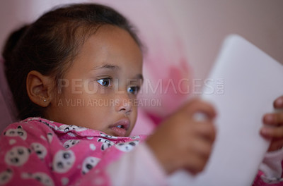 Buy stock photo Shot of a little girl lying in bed using a digital tablet