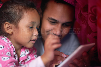 Buy stock photo Shot of a father reading a story to his little girl from a digital tablet while lying under together under a blanket