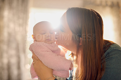 Buy stock photo Shot of a mother kissing her baby girl at home