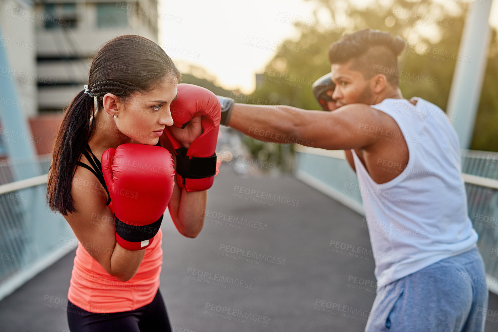 Buy stock photo Shot of a young couple going through some kickboxing routines outdoors on a bridge