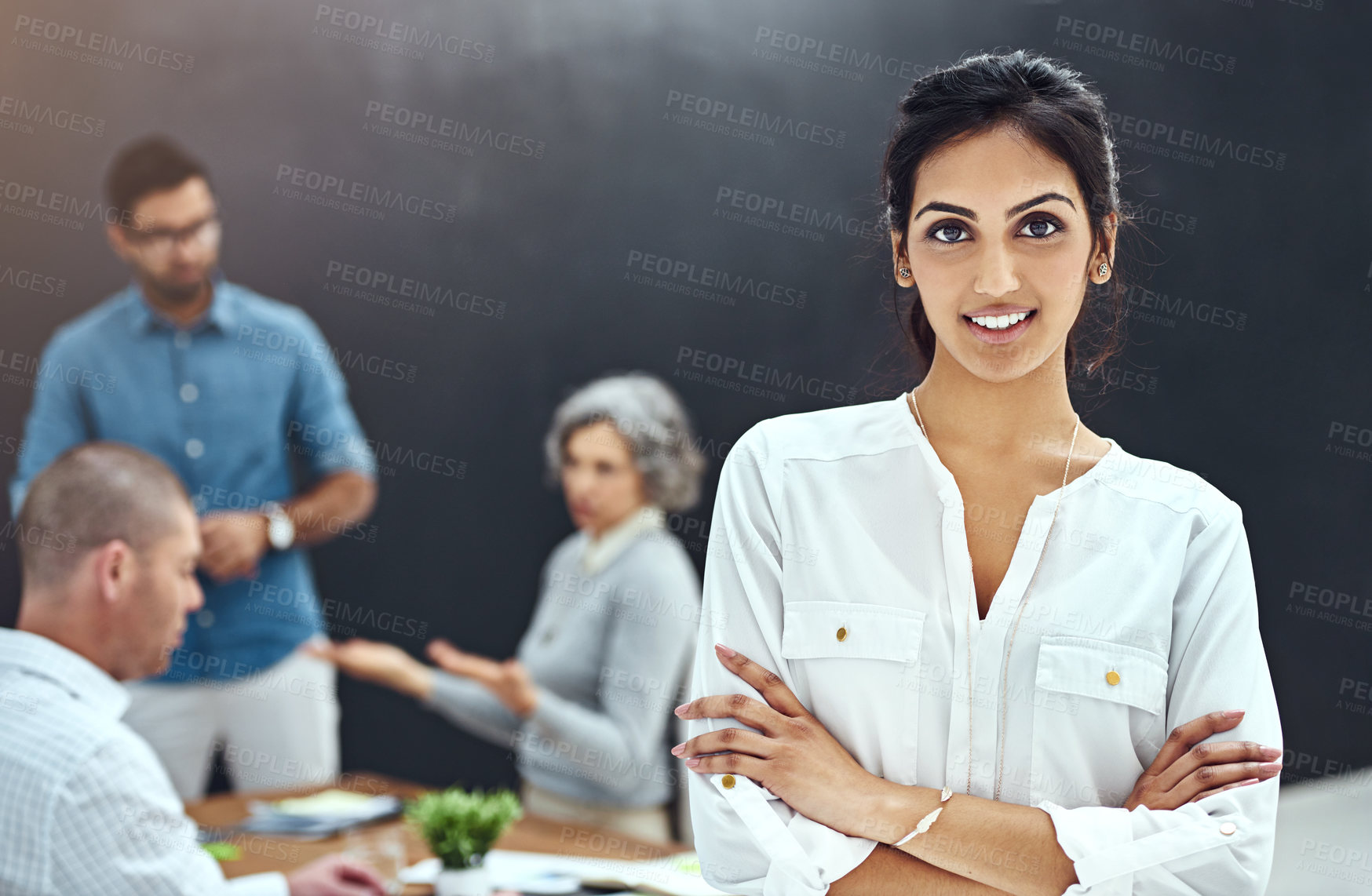 Buy stock photo Portrait of a businesswoman standing with her arms folded in the boardroom while a colleague gives a presentation in the background