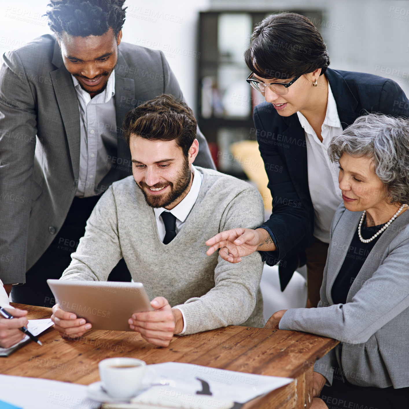 Buy stock photo Cropped shot of a group of businesspeople working together on a digital tablet in an office