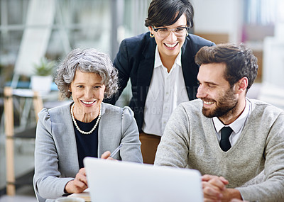 Buy stock photo Cropped shot of a group of businesspeople working together on a laptop in an office