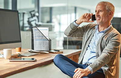 Buy stock photo Shot of a mature businessman talking on the phone while sitting at his desk in an office