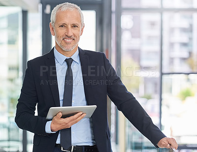 Buy stock photo Portrait of a mature executive using a digital tablet while standing in an office
