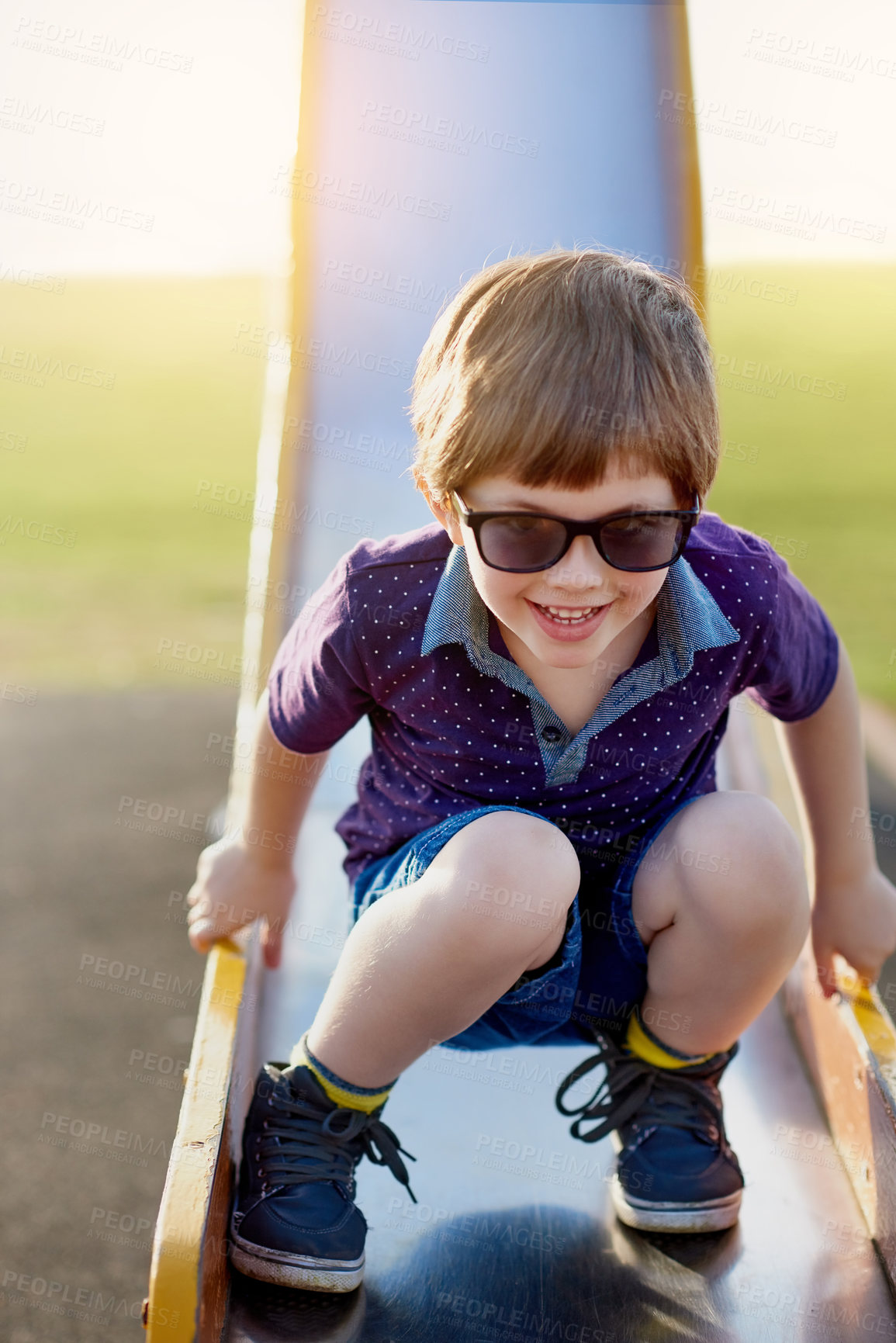 Buy stock photo Boy, child and slide in playground for play, fun and park in summer. Kid, happy and outdoors with children in sunglasses and weekend activity, outing and sunshine for relax and childhood development