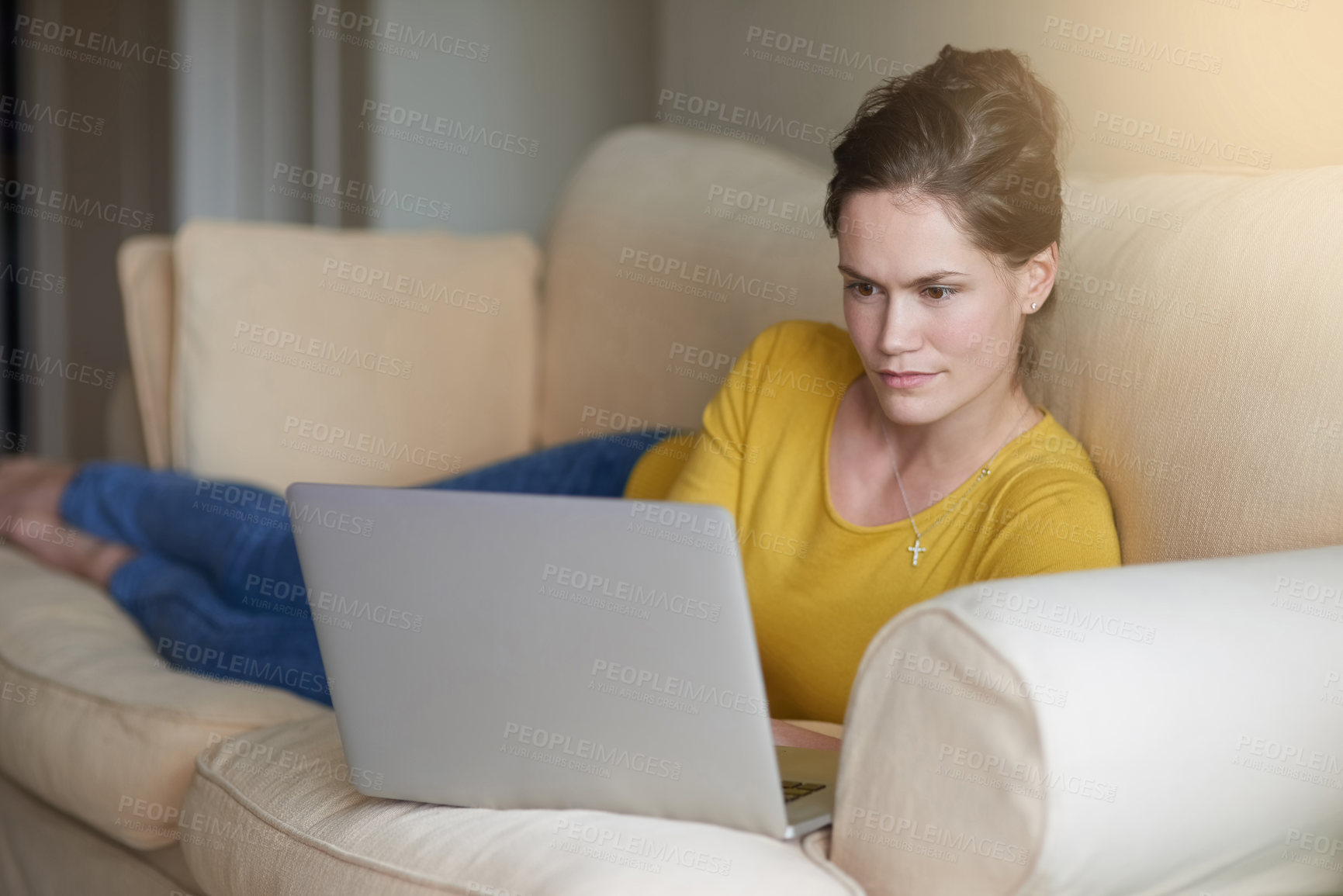 Buy stock photo Shot of an attractive young woman using her laptop on the sofa at home